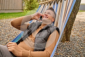 Joyous vacationer having a phone conversation outdoors