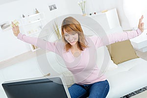 Joyous woman holding bankcard and looking at computer screen