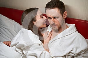 Joyous woman telling secret to her lover in hotel room