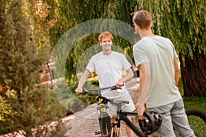 Joyous young bicyclist chatting with his frien