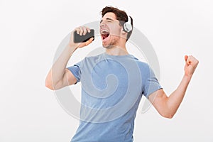 Joyous young man 30s in casual t-shirt listening to music via wi