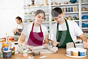 Joyous young man and woman sculpting handmade cups