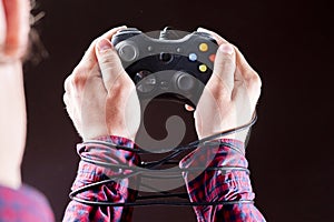 joystick wire wrapped around persons hands, video games addiction concept b