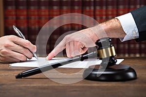 Judge Assisting Client To Sign Legal Document In Courtroom