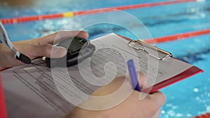 Judge at competition in pool. Close-up of the judge`s hand in the pool which records the testimony in the sheet