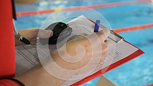 Judge at competition in pool. Close-up of the judge`s hand in the pool which records the testimony in the sheet