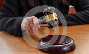 Judge female hand hold a gavel on law court bench, close up. Justice and punishment concept