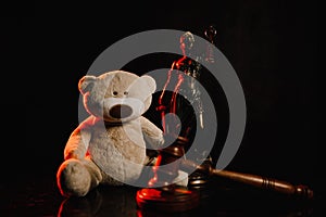 Judge gavel, figure of lady justice and teddy bear in a court room. Law and children concept
