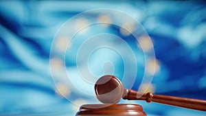 A judge gavel with a flag of European Union on background. Close up of wooden hammer and legal lawyer books or codex