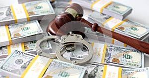 Judge gavel and handcuffs among packs of money cash on table