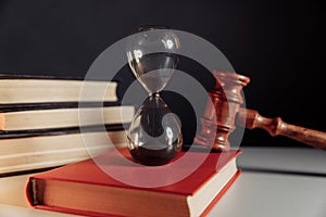 Judge gavel and hourglass on red book close-up