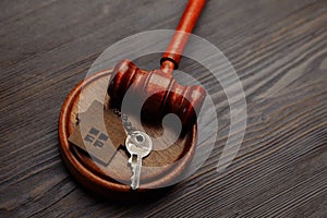 Judge gavel and key chain in shape of two splitted part of house on wooden background. Concept of real estate auction or