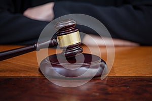 Judge gavel on law court desk, blur female crossed hands, close up view