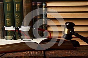 Judge gavel and legal book collection with eyeglasses on wooden