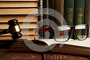 Judge gavel and legal book collection with eyeglasses on wooden