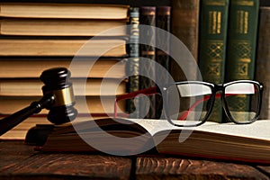 Judge gavel and legal book collection with eyeglasses on wooden