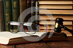 Judge gavel and legal book collection with eyeglasses on wooden