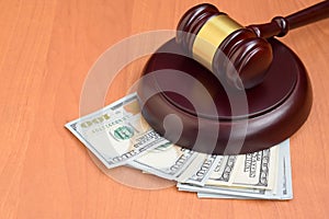 Judge gavel and money on brown wooden table. Many hundred dollar bills under judge malice on court desk. Judgement and bribe