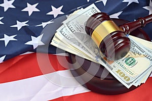 Judge gavel and money on United States of America flag. Many hundred dollar bills under judge malice on USA flag. Judgement and