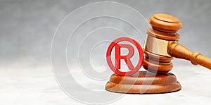 Judge gavel and red trademark sign on gray