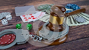 judge gavel and set of playing cards with dices, money and chips, on wooden table. Casino concept