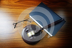 Judge gavel with sound board, blue statute book and glasses on a