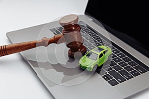 Judge gavel and toy car on laptop computer keyboard. Symbol of law, justice and online car auction.