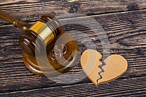 Judge gavel and wedding rings, with a broken heart. Divorce proceedings, marriage contract, alimony