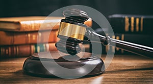 Judge gavel on a wooden desk, law books background