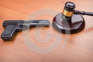Judge hammer, pistol on the background of wooden table. Concept is not legally carrying weapons. concept of the court and the righ