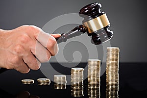 Judge Hands Hitting Gavel On Stacked Coins