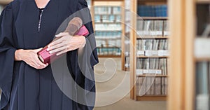 Judge holding book in front of library book shelves