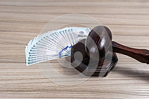 Judge\'s ceremonial wooden gavel on a stand next to US dollar bills