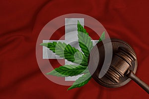 Judge's gavel and cannabis leaf on the Swiss flag background. The concept of legalization of marijuana in Switzerland