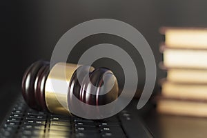 Judge`s gavel on computer keyboard with copy space with law books on the background