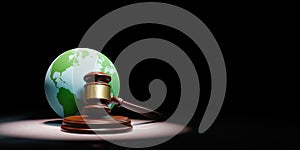 Judge's Gavel with Earth Planet Spotlighted on Black Background photo
