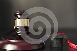 Judge`s gavel and graduation cap on black wooden table