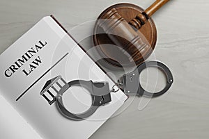 Judge`s gavel, handcuffs and Criminal law book on wooden background, flat lay