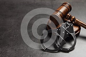 Judge`s gavel and handcuffs on grey, space for text. Criminal law concept