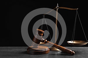 Judge`s gavel and scales on grey table against background. Criminal law concept