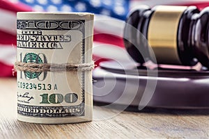 Judge`s hammer gavel. Justice dollars banknotes and usa flag in the background. Court gavel and rolled banknotes.