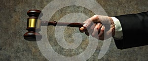 A judge's hand grips a gavel, raised and ready to strike down, symbolizing authority and decision-making in a photo