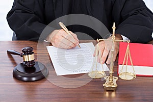 Judge signing contract paper at desk