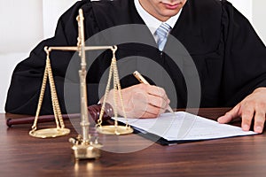 Judge signing document at table in courtroom