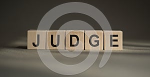 Judge - word from wooden blocks with letters, Judge, try, referee, adjudicate concept, black leather background