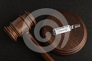 Judges gavel and glass ampoule vial with coronavirus COVID-19 vaccine. Concept laws against covid-19 photo