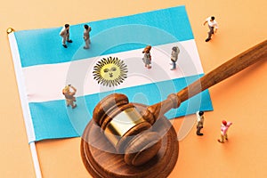 Judicial hammer, Argentine flag and plastic toy men on a colored background, the concept of trials in Argentine society