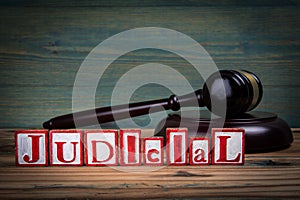 JUDICIAL. Red alphabet letters and judge's gavel on wooden background. laws and justice concept