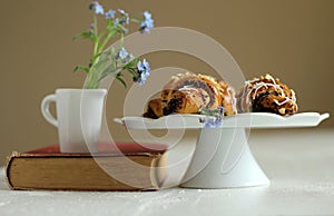 Jug with flowers forget-me-not on vintage book and croissants