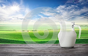 Jug of fresh milk against background of wavy pasture